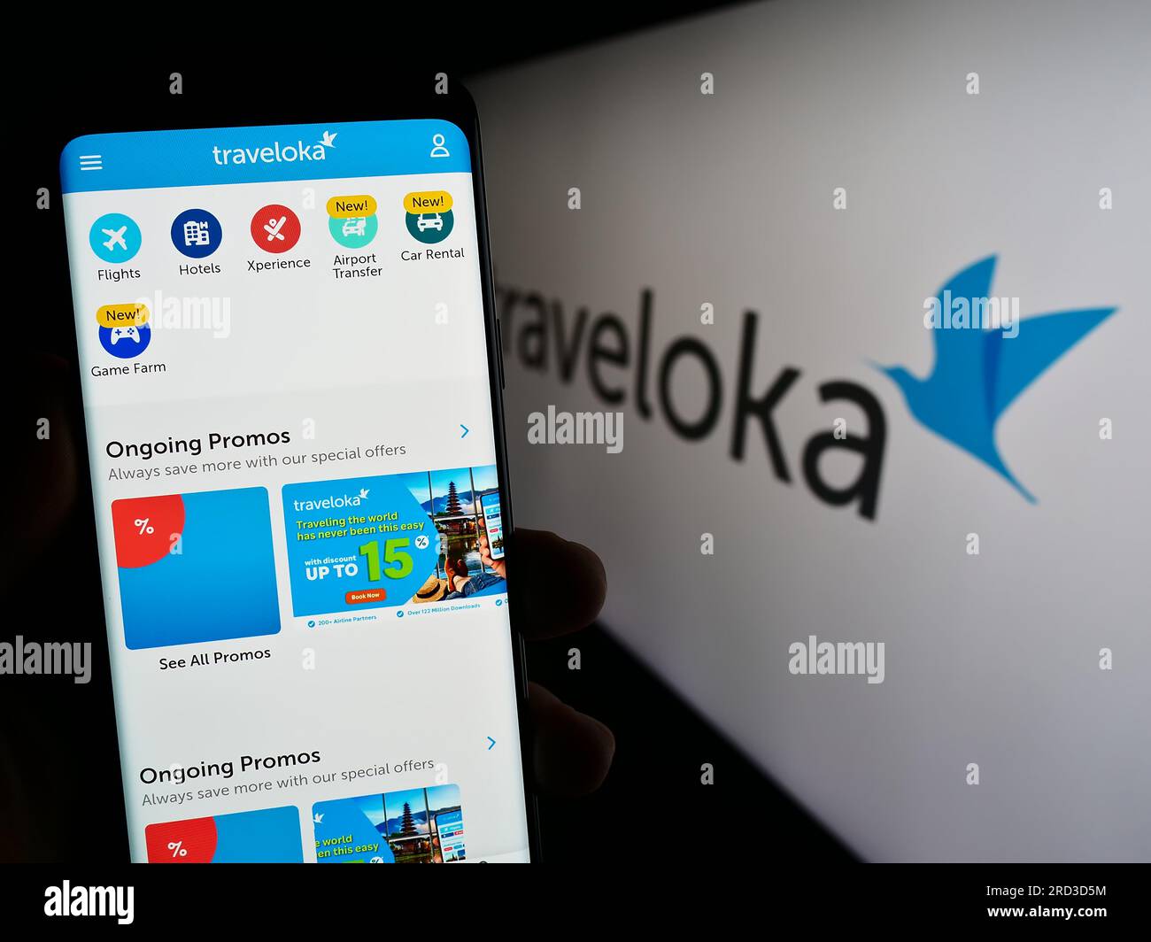 Person holding smartphone with webpage of Indonesian travel company Traveloka on screen in front of logo. Focus on center of phone display. Stock Photo