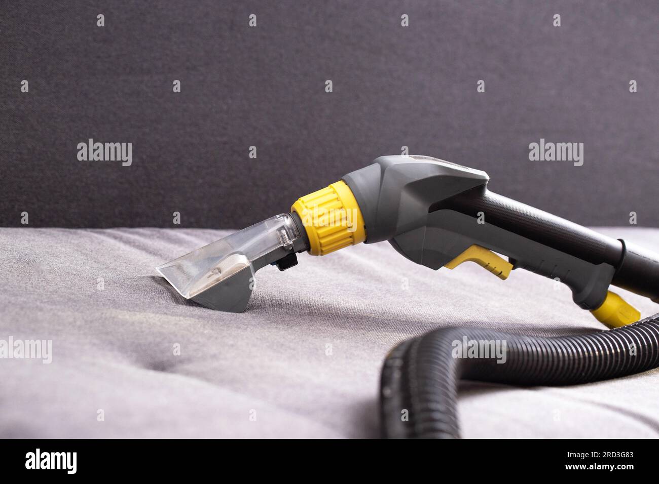 A professional washing vacuum cleaner for dry cleaning lies on a black sofa, close-up. Concept service for cleaning upholstered furniture. Stock Photo