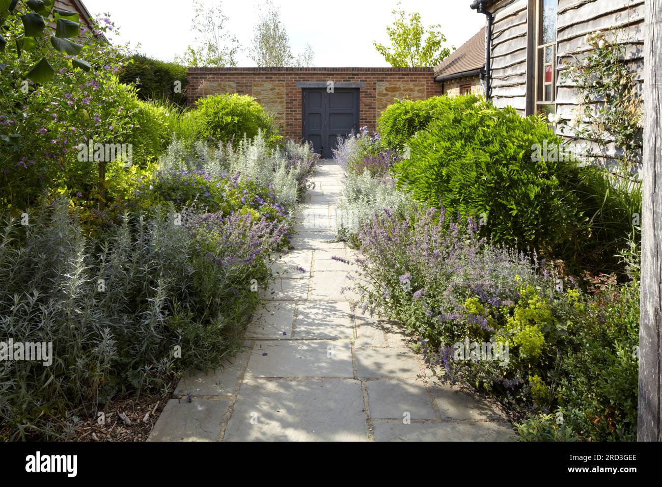 View from front entrance to garden wall with flower border either side of path. Manor Barn, Faringdon, United Kingdom. Architect: None, 2015. Stock Photo