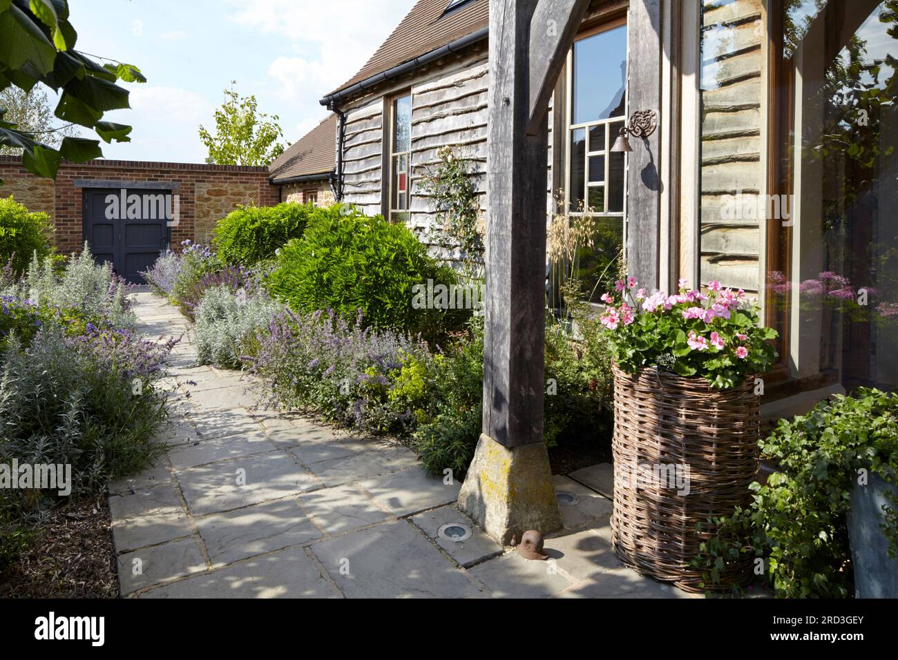 View from front entrance to garden wall with flower border either side of path. Manor Barn, Faringdon, United Kingdom. Architect: None, 2015. Stock Photo
