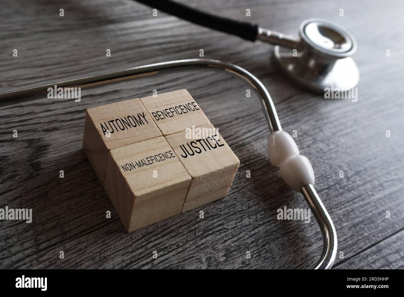 Stethoscope and wooden cubes with text AUTONOMY, BENEFICENCE, NON-MALEFICENCE, and JUSTICE. The four pillars of medical ethics concept. Stock Photo