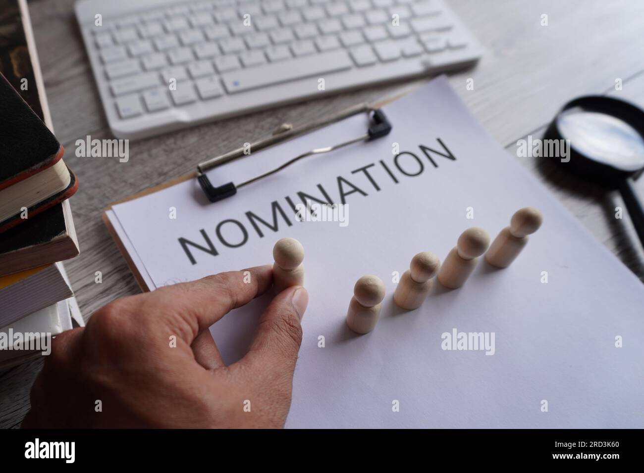 Hand pick wooden doll and text NOMINATION. Nominating a candidate for promotion. Select and designate an employee. Career advancement and social growt Stock Photo