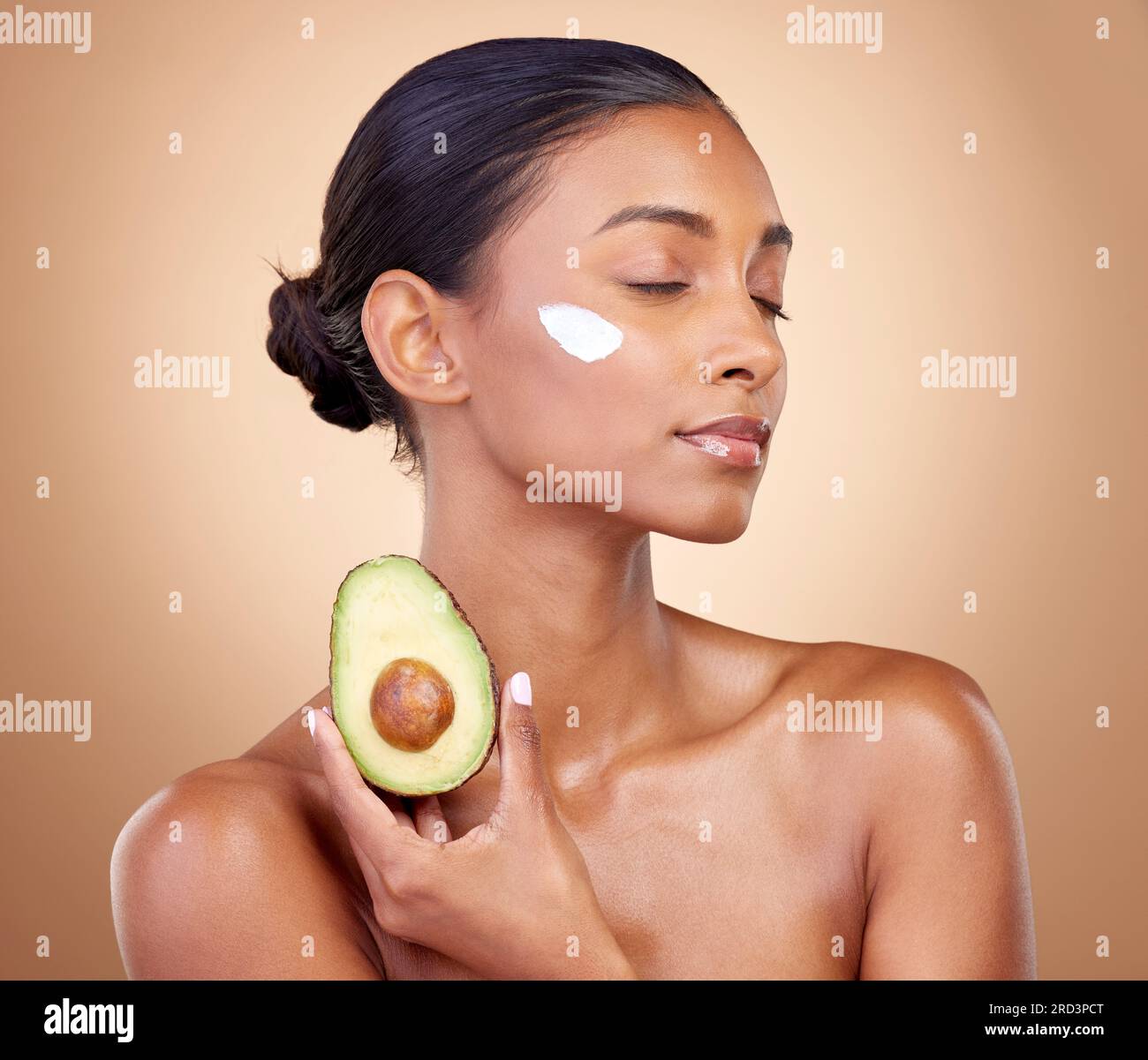 Woman, avocado and cream for skincare, natural beauty and vitamin c benefits on studio, brown background. Young calm person or model with facial Stock Photo