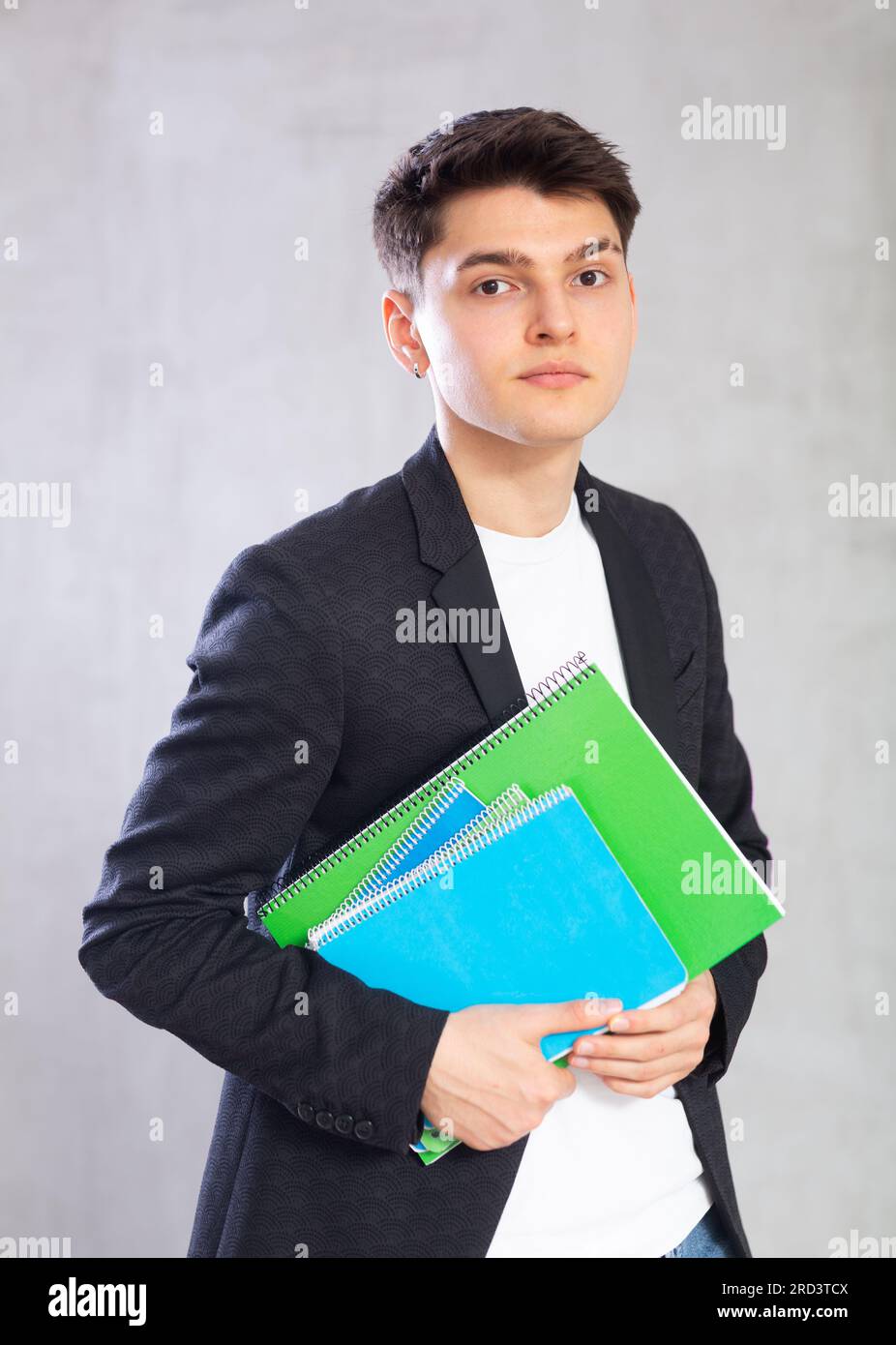 Focused young guy holding stack of notebooks Stock Photo - Alamy