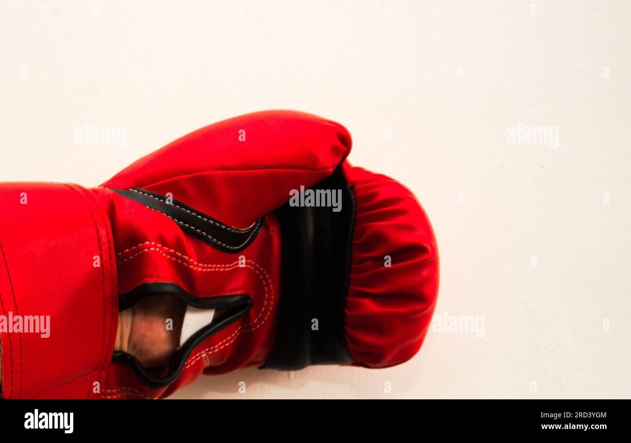 A man's left hand in a red, Lonsdale branded boxing glove;  mainly white background, fight, fighting, defend,  aggression, box, combat, hit Stock Photo