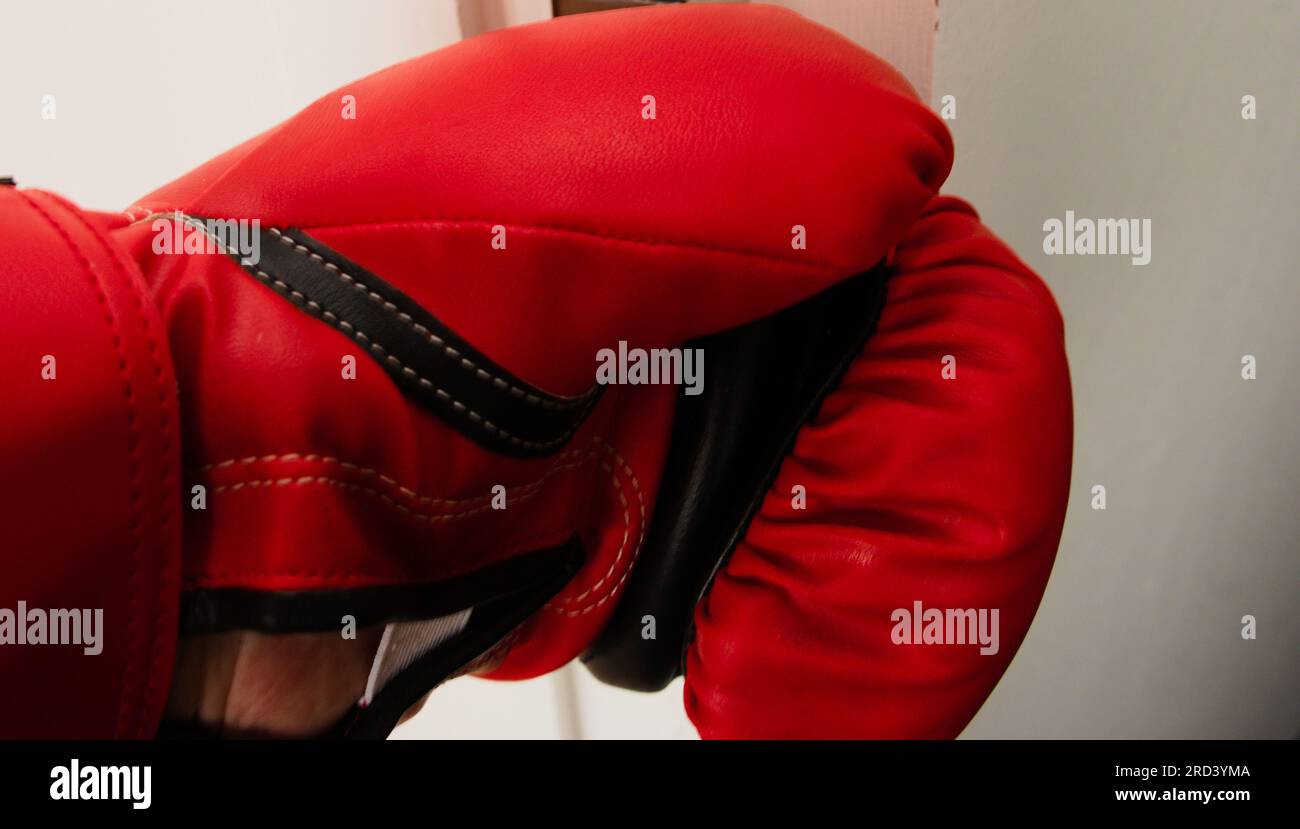 A man's left hand in a red, Lonsdale branded boxing glove;  white background, fight, fighting, defend,  aggression, box, combat, hit Stock Photo