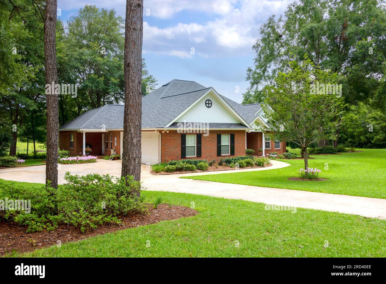 Traditional style brick house with black shutters, situated on a large