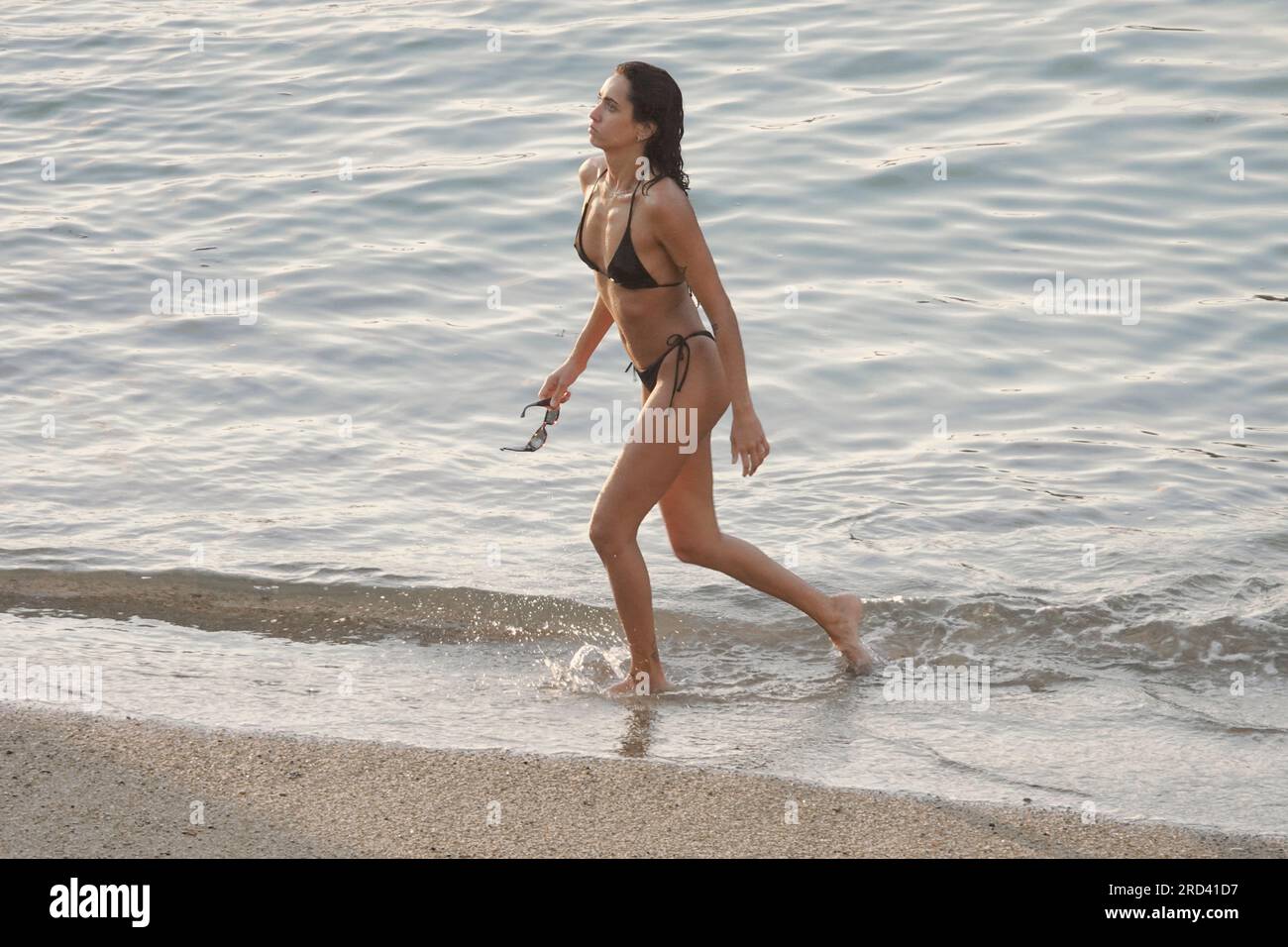Biarritz, France, July, 2023  Lady walks ashore after an evening dip in the sea on the Plage du Port Vieux, in Biarritz Stock Photo
