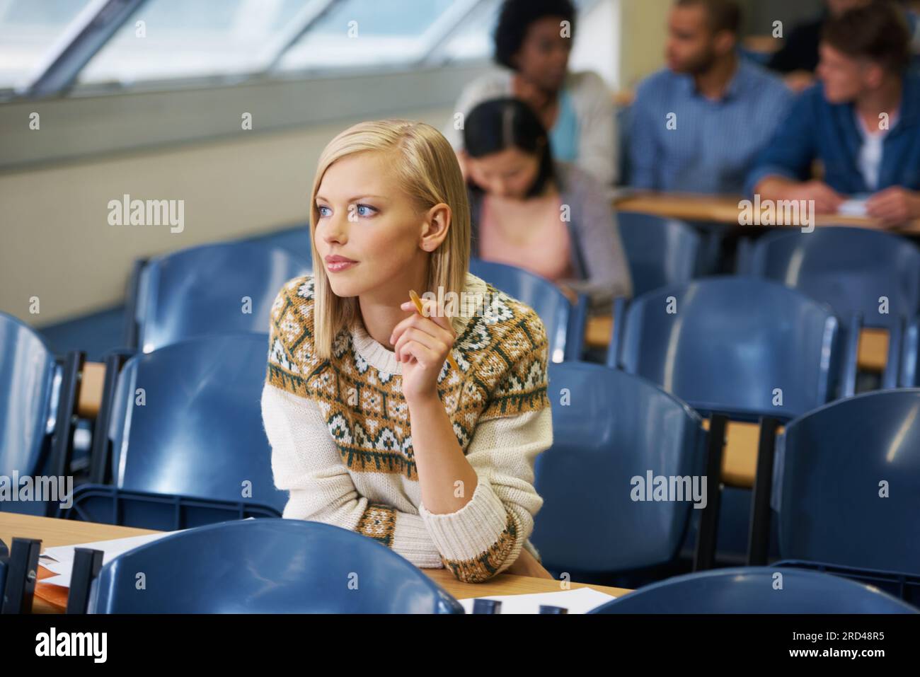 The last exam before the real world begins. A group of students sitting in an exam room. Stock Photo