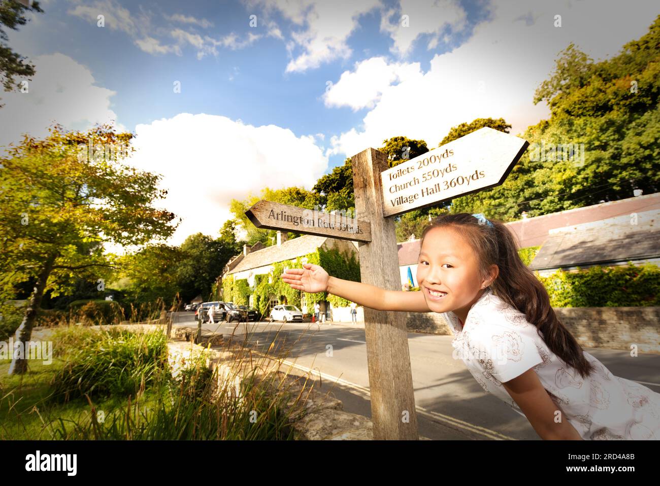 Arlington Row in Bibury, Cotswolds, road sign to famous Arlington Row, a girl pointing to the road sign, travel excitement Stock Photo