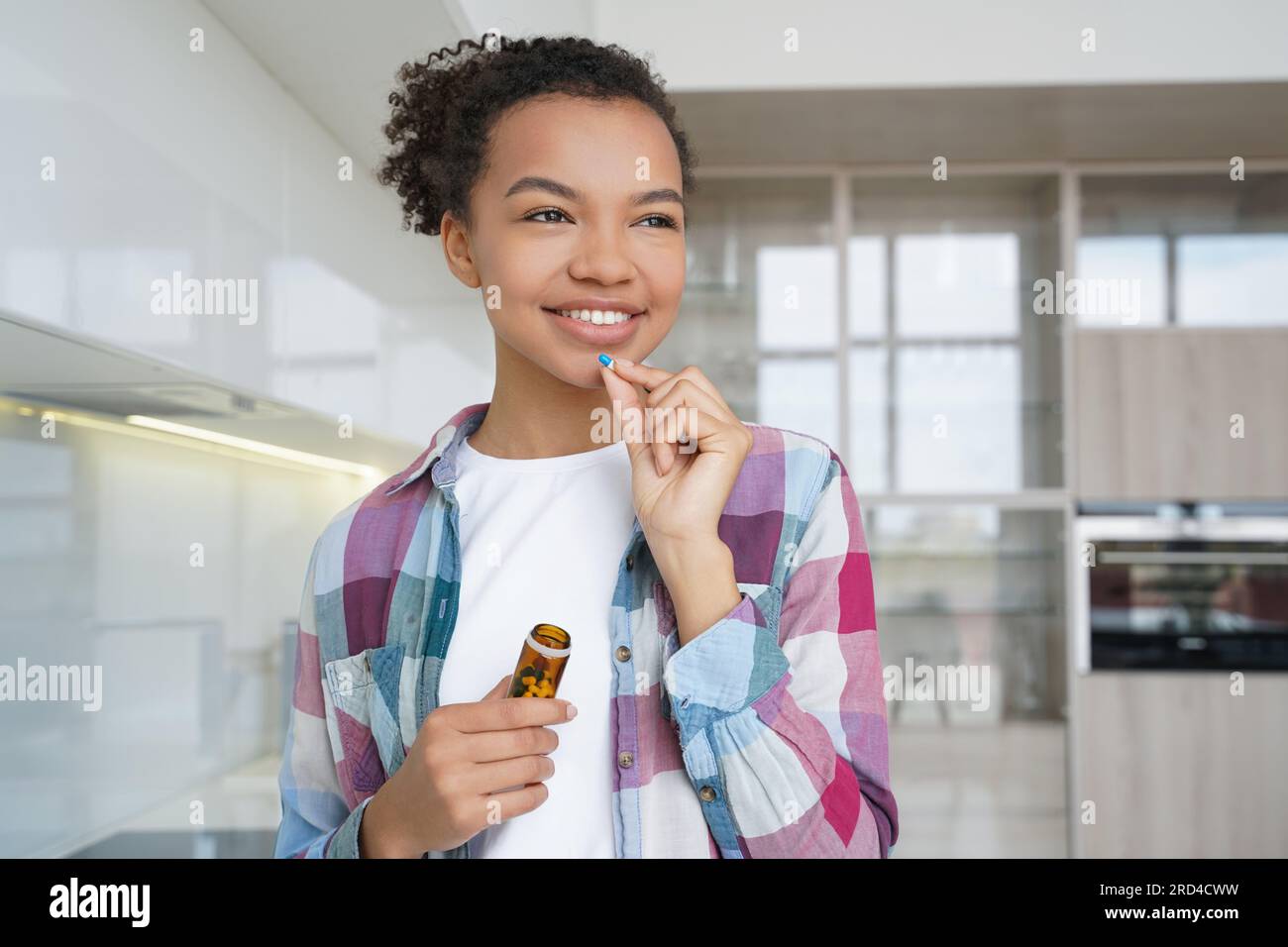 Happy girl takes pills for wellness, promoting healthy lifestyle at home. Stock Photo
