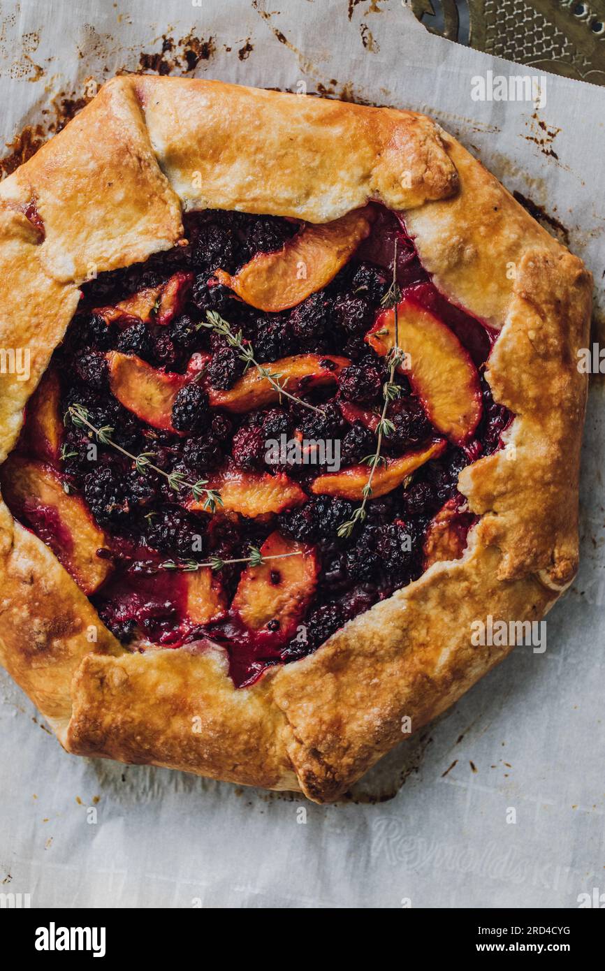 directly above homemade blackberry, peach, thyme galette on parchment paper Stock Photo