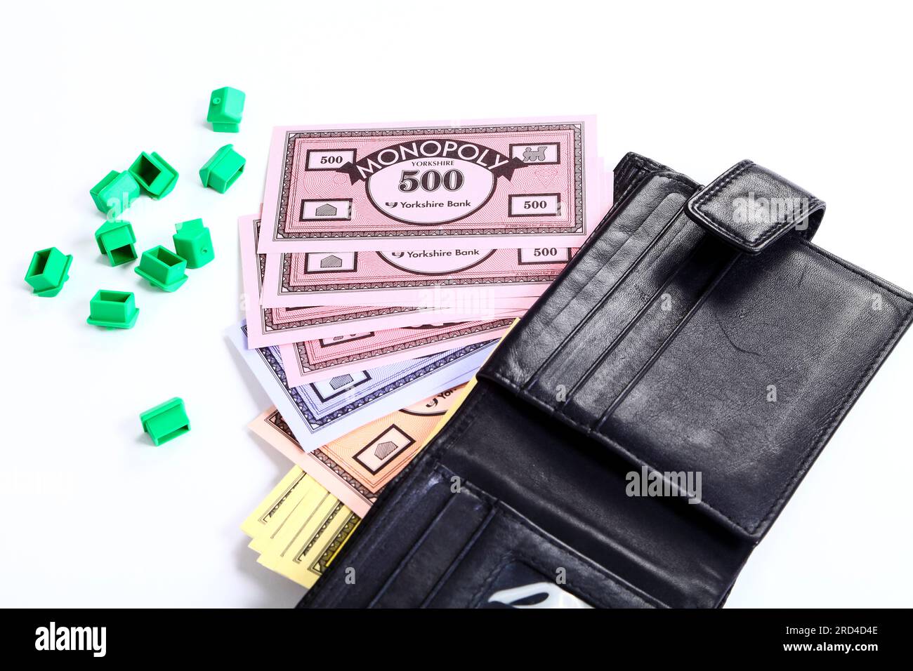 Monopoly green houses and money spilling from a wallet Stock Photo