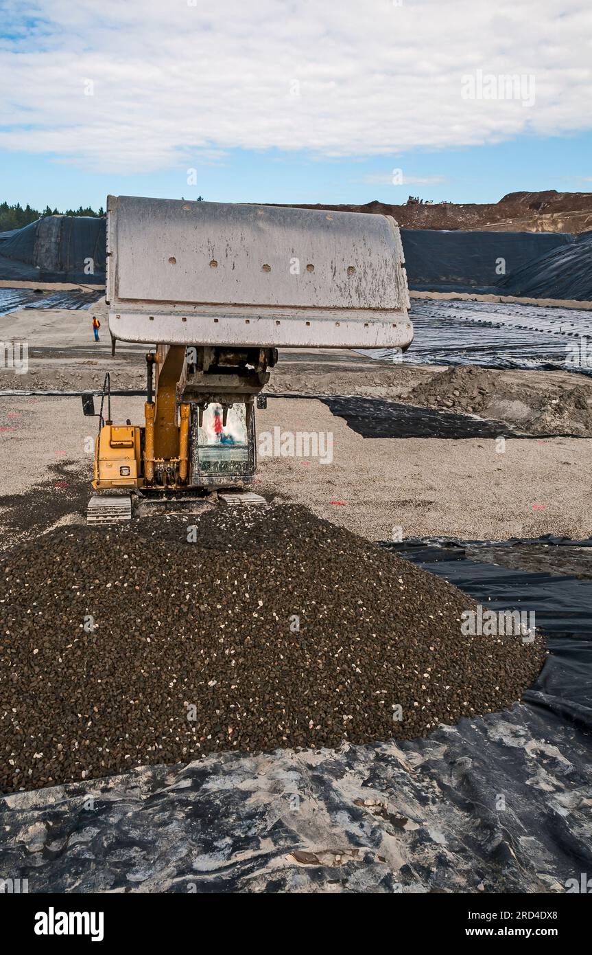 Workers and a power shovel work to excavate and install geomembrane in