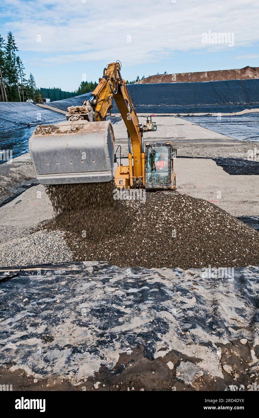 Workers and a power shovel work to excavate and install geomembrane in