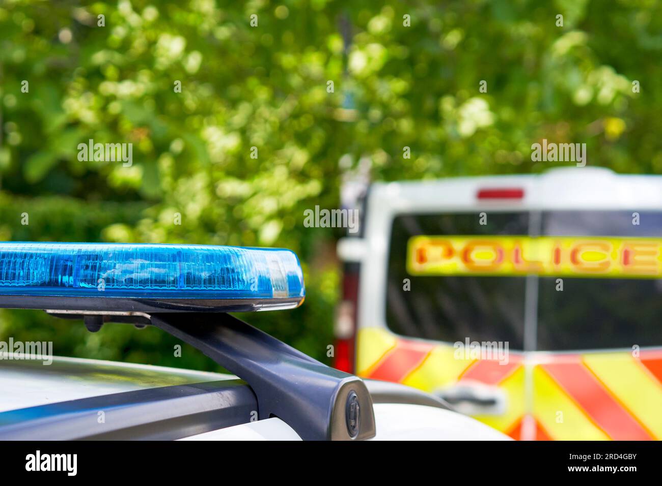 Blue light mounted on the roof of a Police car with another Police vehicle in the background Stock Photo