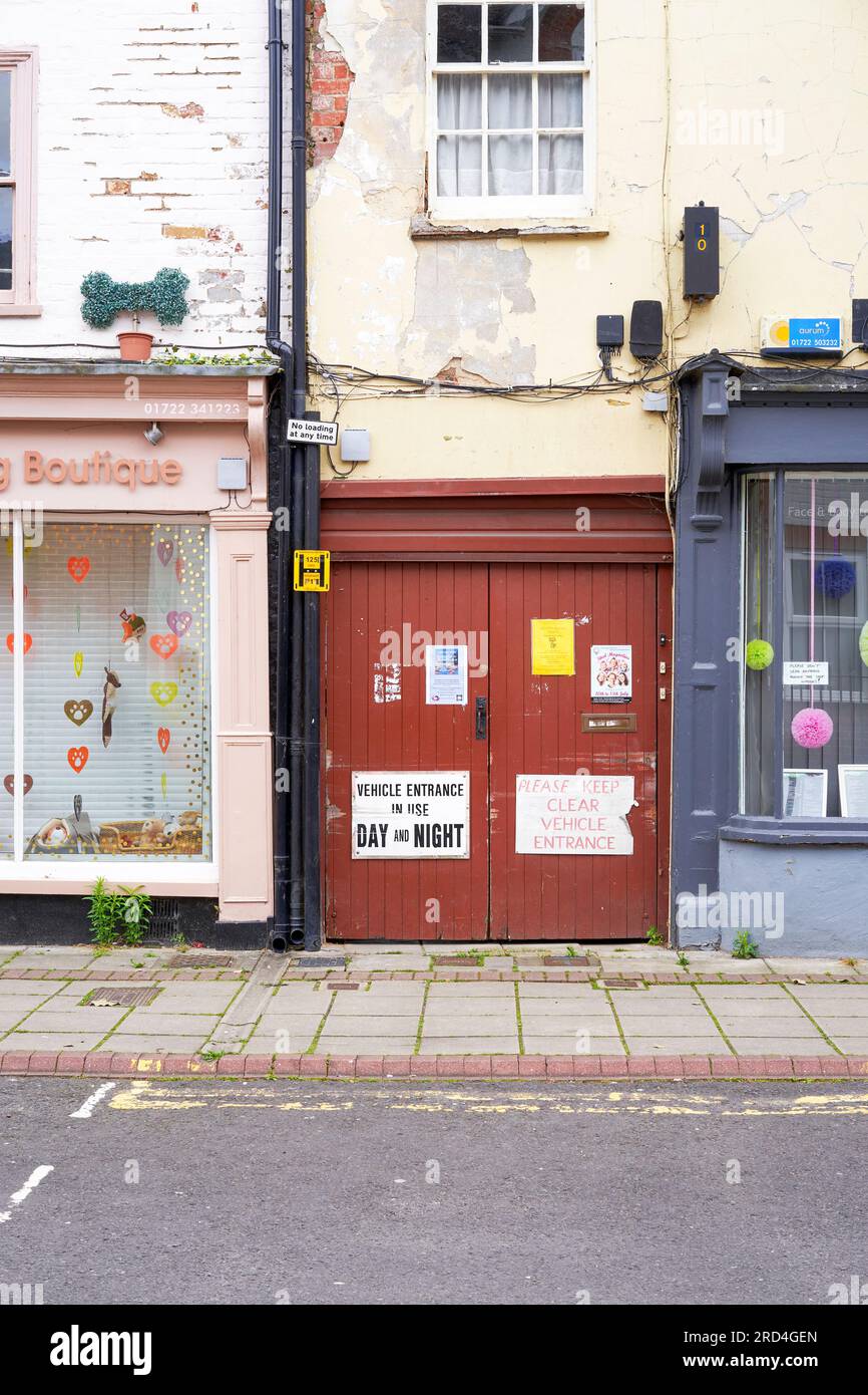 Old brown painted wooden doors with posters and flyers between shop windows Stock Photo