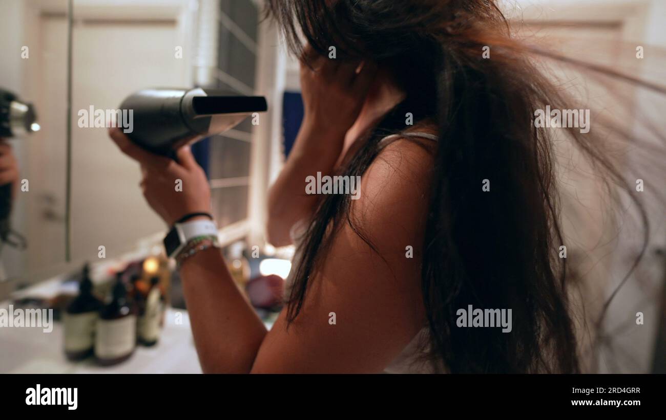 Woman dries hair in front of bathroom mirror Stock Photo - Alamy