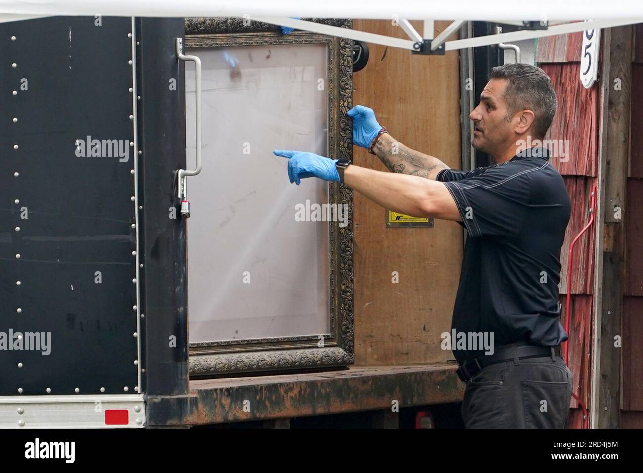 Authorities remove a picture frame as they search the home of suspect
