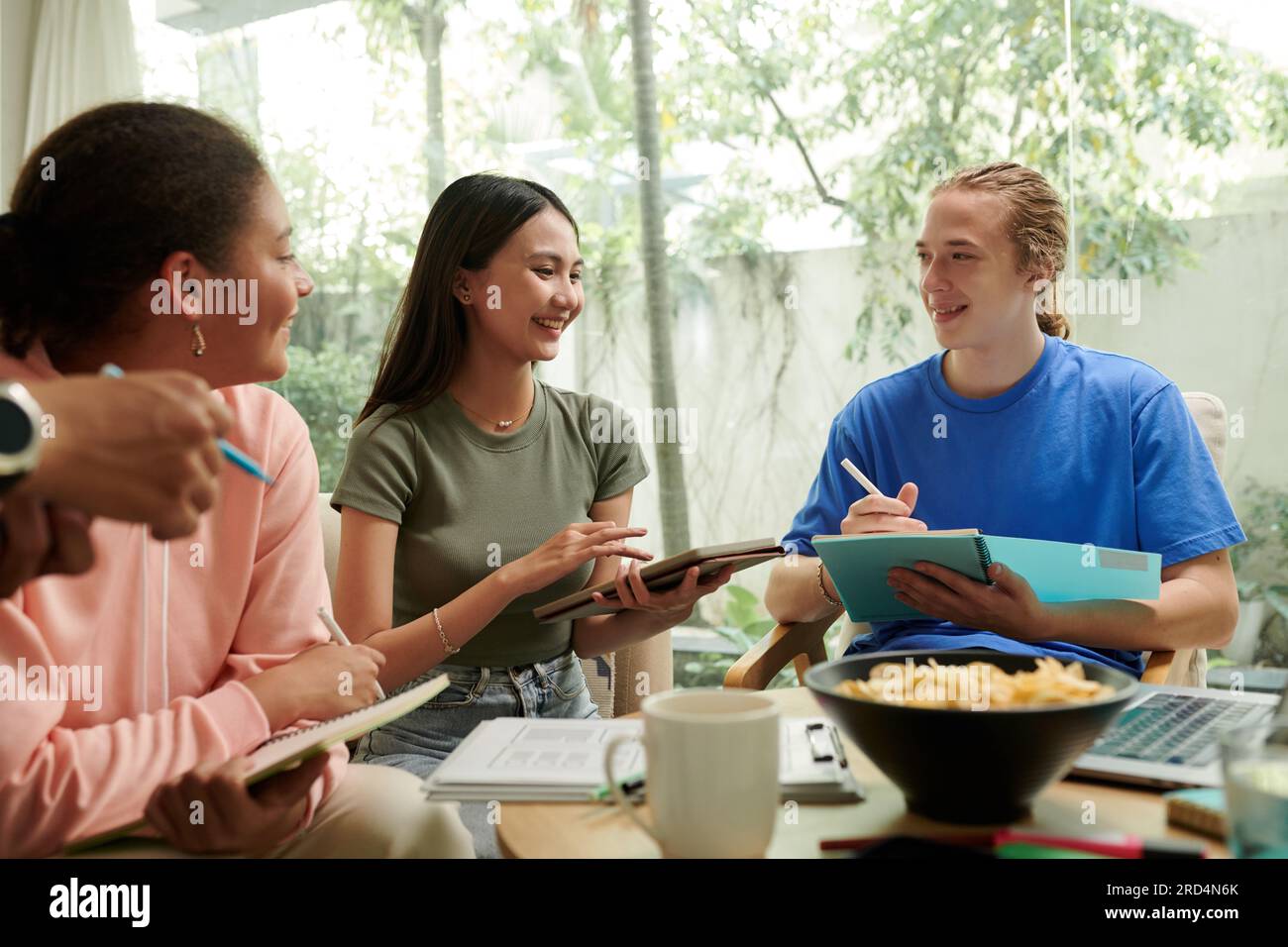 Group of joyful college students brainstorming ideas for mobile application Stock Photo