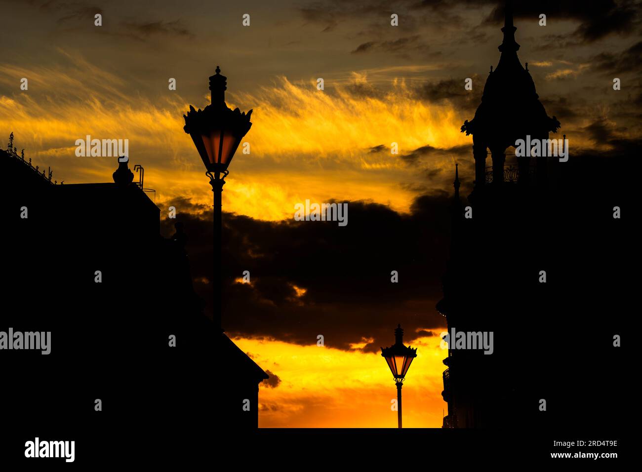 Street lights and silhouettes of historical buildings against an orange sky at twilight time Stock Photo
