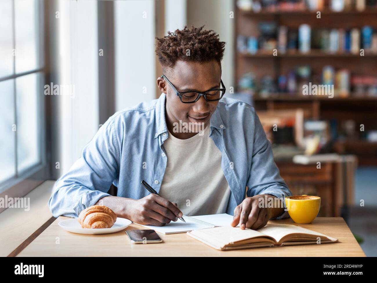 Focused guy student taking notes at table in coffee shop Stock Photo