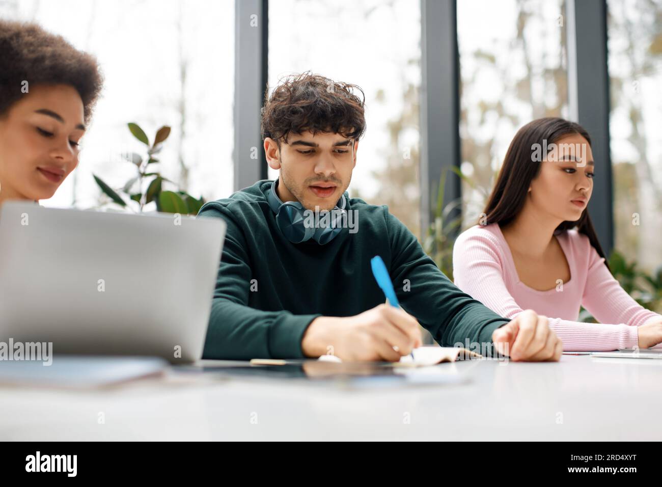Study process concept. Multiracial students sitting at desk learning together, preparing for university exams Stock Photo