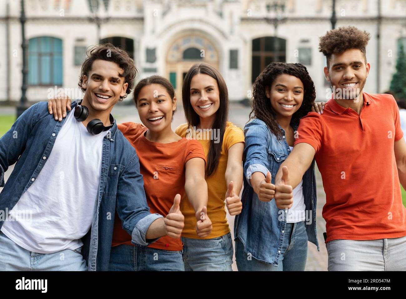 We Like Learning. Multiethnic Students Gesturing Thumbs Up While Standing Outdoors Stock Photo