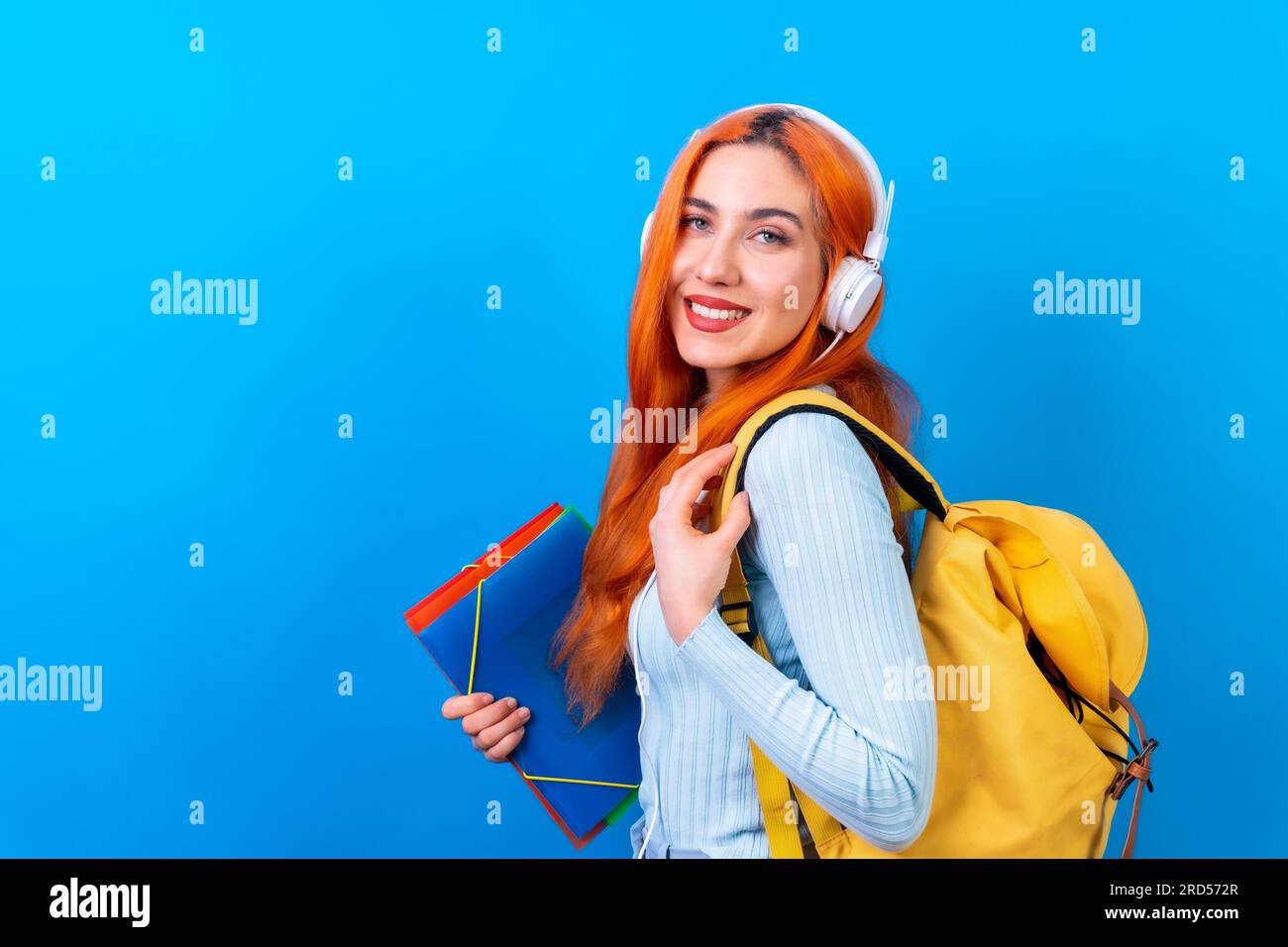 Redhead woman in studio photography dancing college student on a blue background, back to school Stock Photo