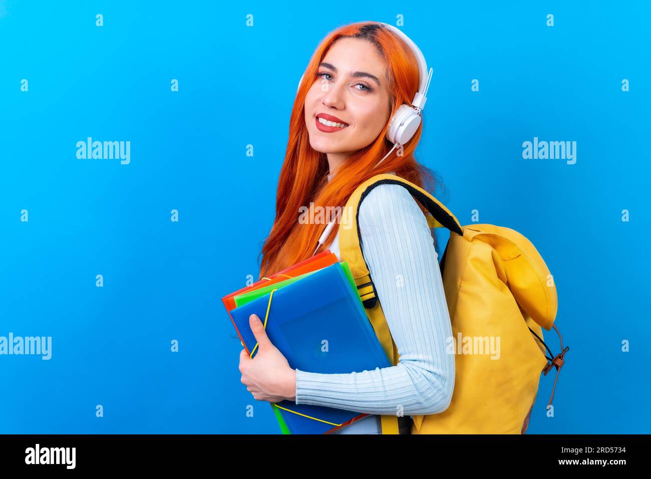 Redhead woman in studio photography dancing college student on a blue background, back to school Stock Photo