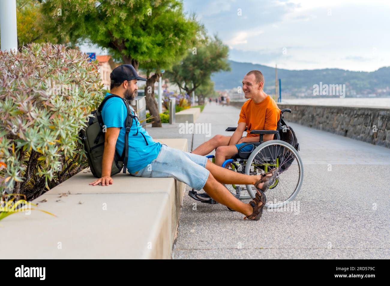 A disabled person in a wheelchair next to the beach with a friends ...