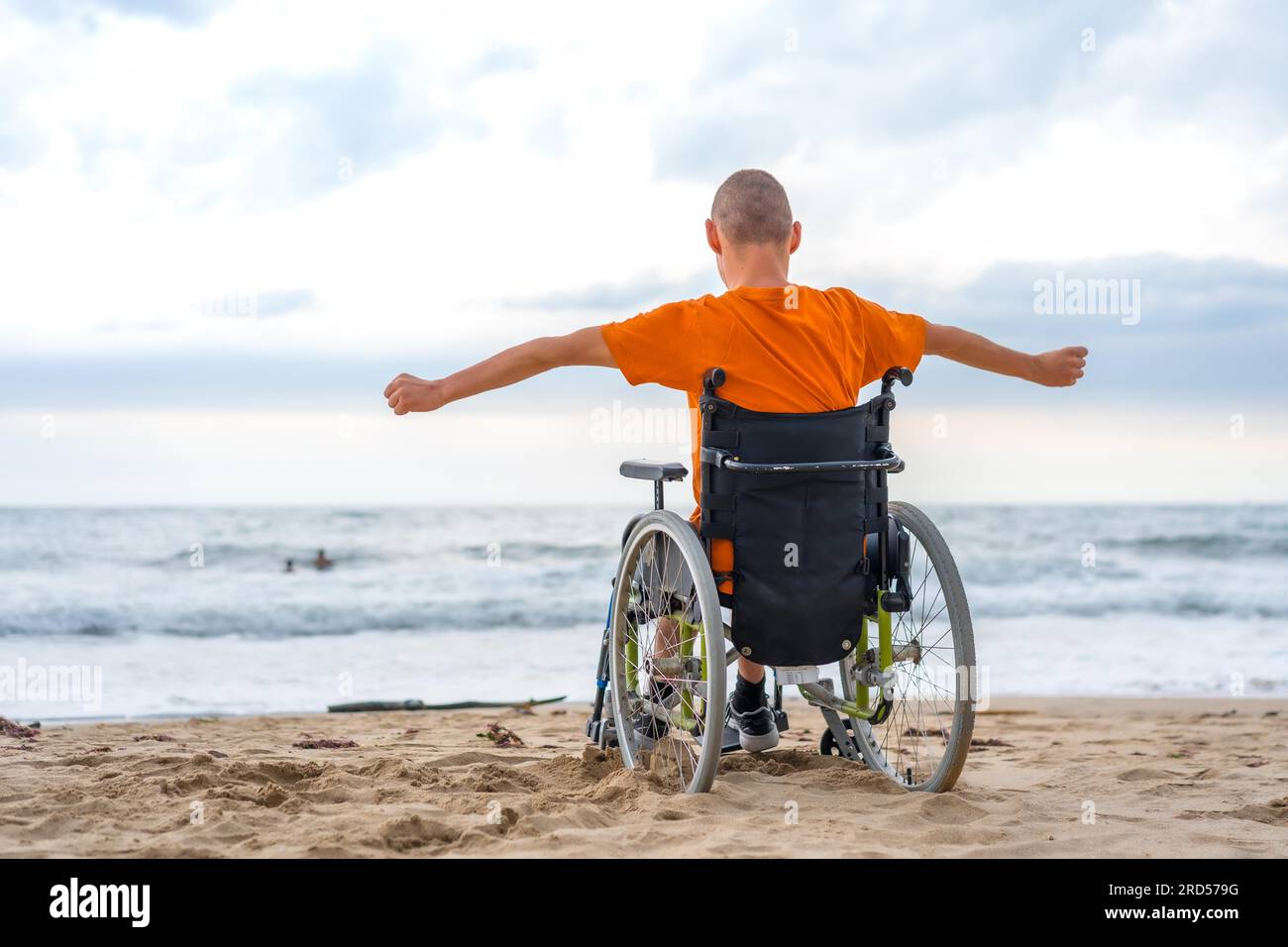 A disabled person on his back in a wheelchair on the beach Stock Photo