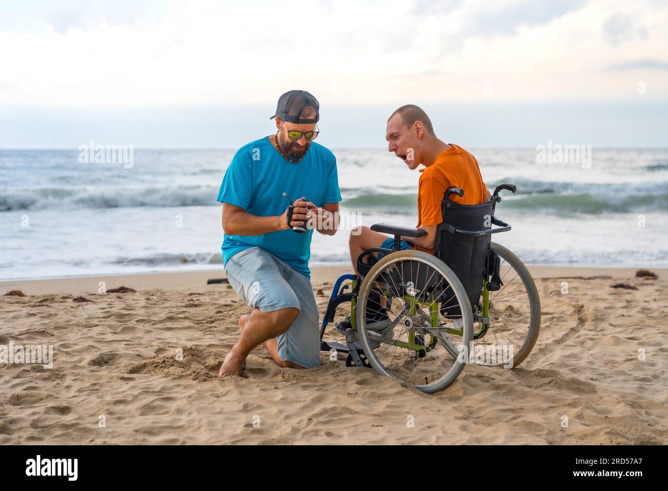 A disabled person in a wheelchair on the beach having fun with a friend