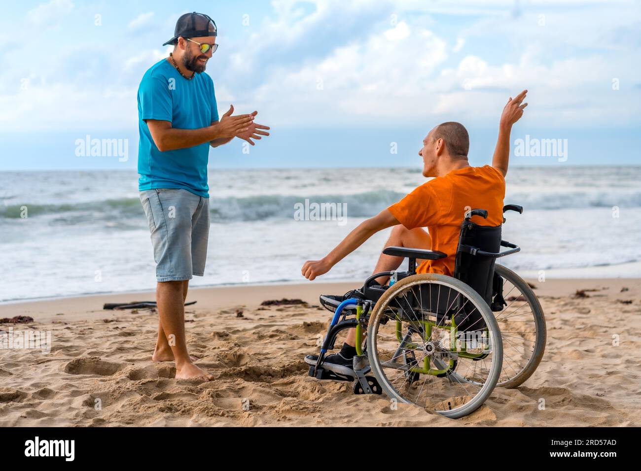 A disabled person in a wheelchair on the beach with a friend having fun
