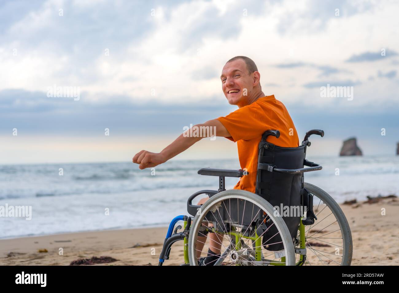 A disabled person on his back in a wheelchair on the beach in summer by