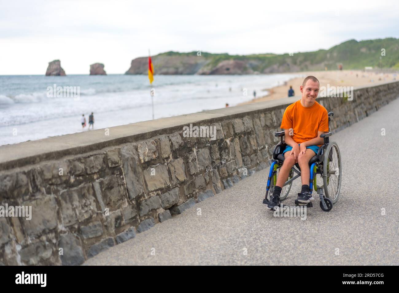 A disabled person in a wheelchair by the beach, having fun in summer ...
