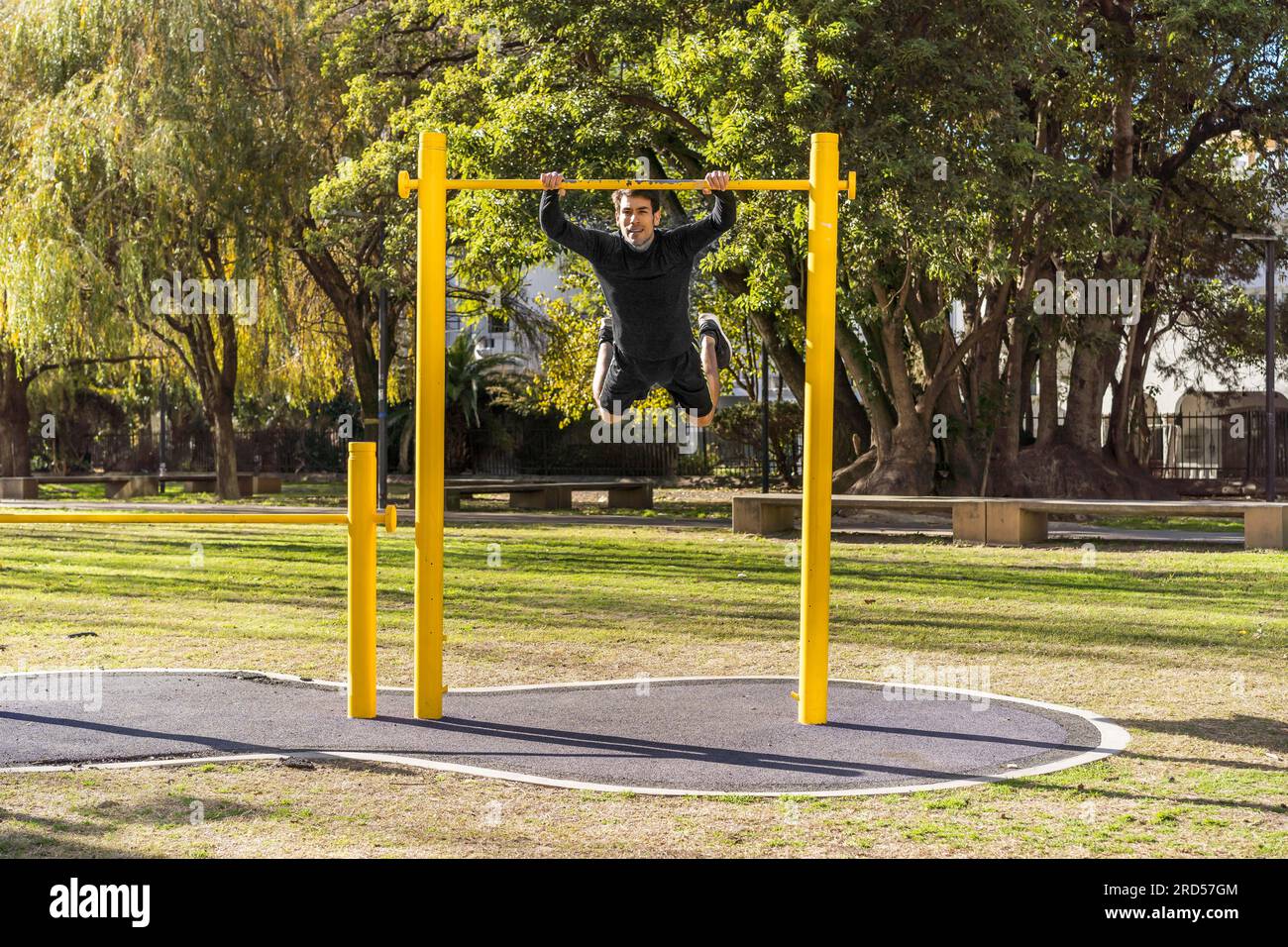 Attractive athlete doing exercises on a crossbar in a public car Stock