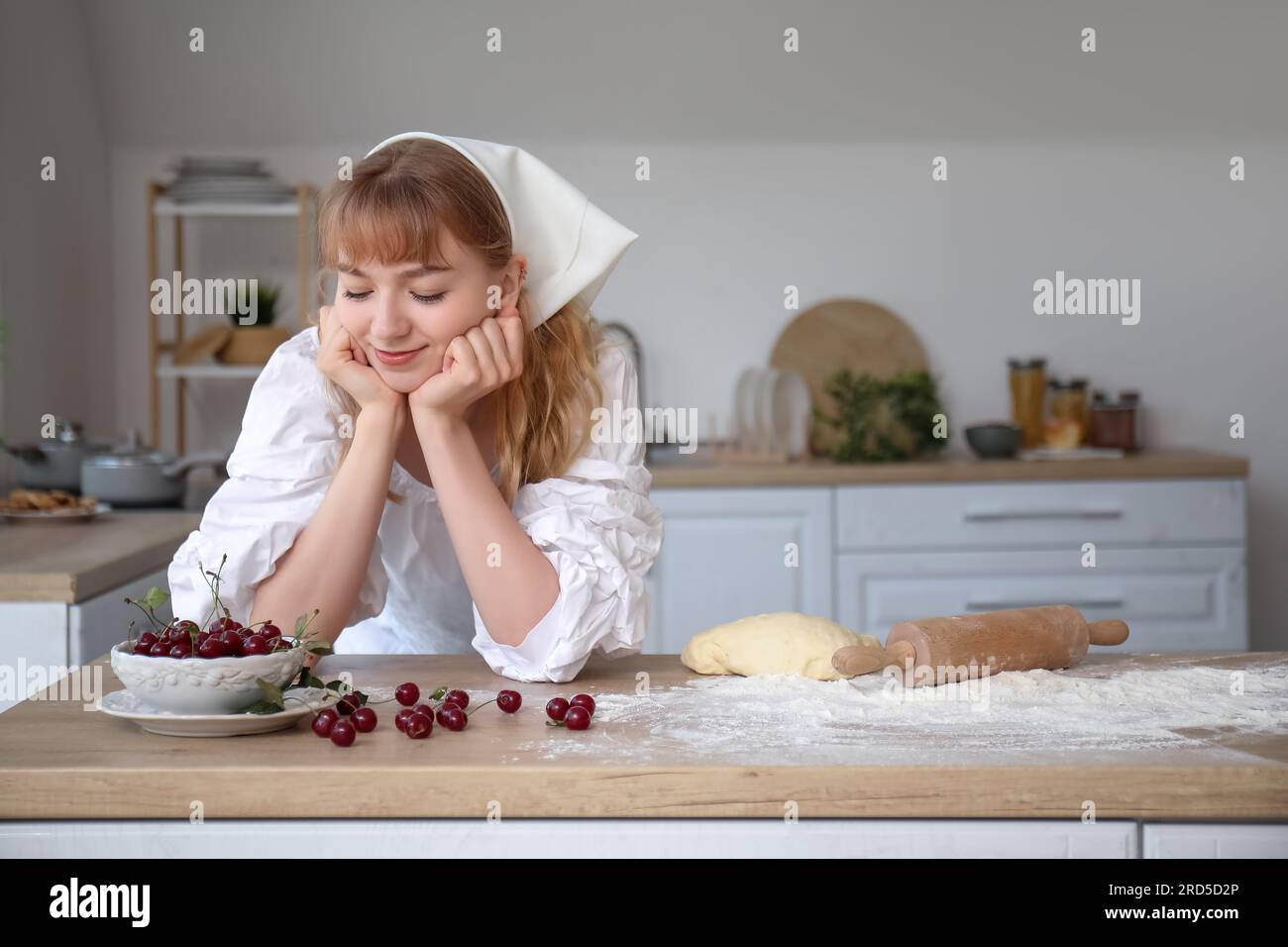 https://c8.alamy.com/comp/2RD5D2P/beautiful-young-woman-with-bowl-of-cherries-rolling-pin-and-dough-on-table-in-kitchen-2RD5D2P.jpg