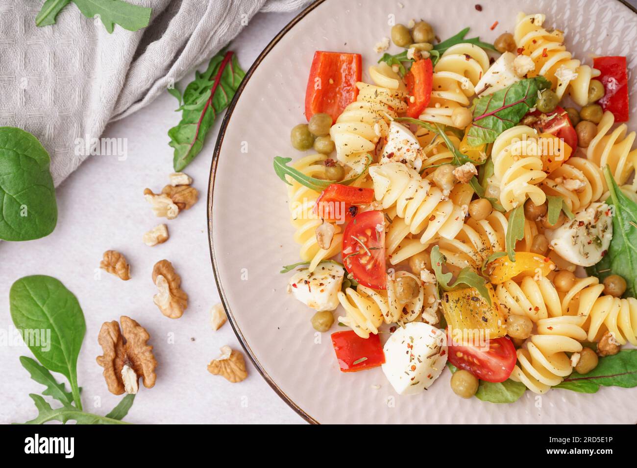 Plate of tasty pasta salad with pepper and peas on white background