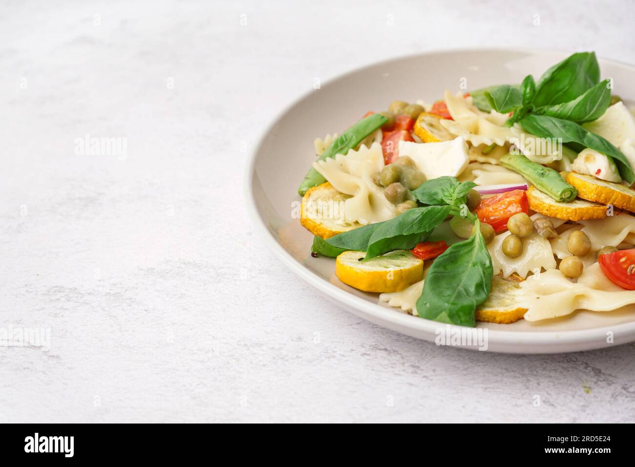 Plate of tasty pasta salad with peas and basil on white background Stock Photo Alamy
