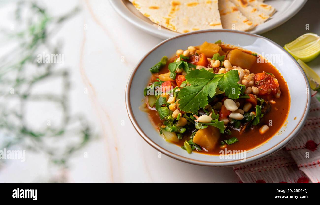 Mexican cuisine, chicken pozole served with radishes, lemons and toast
