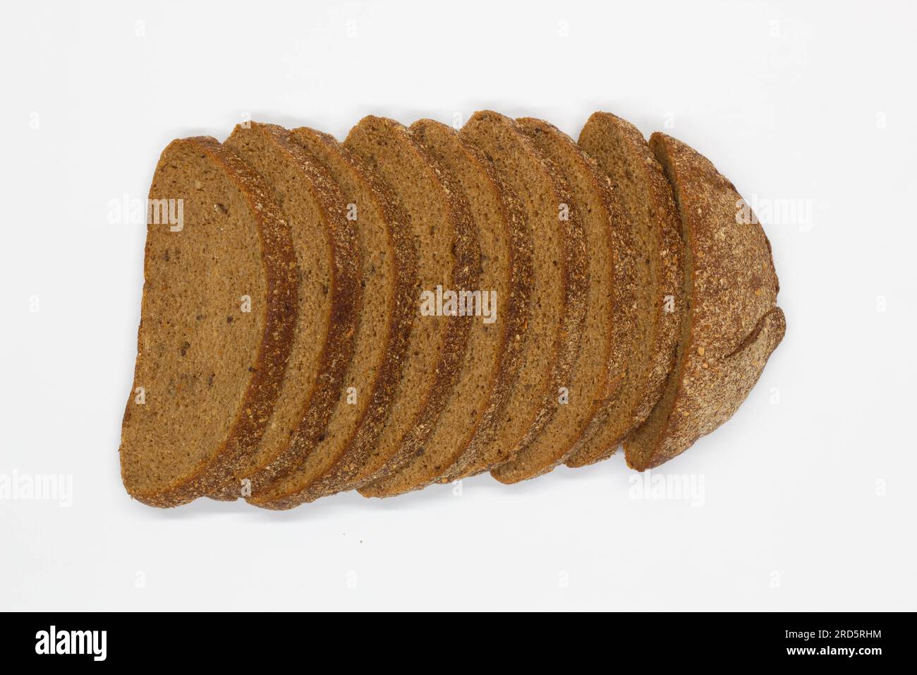 Sliced black bread. Dark rye bread with cumin cut into even pieces on a white background. Wheat black bread on the table. Isolated. Bran from grain. Stock Photo