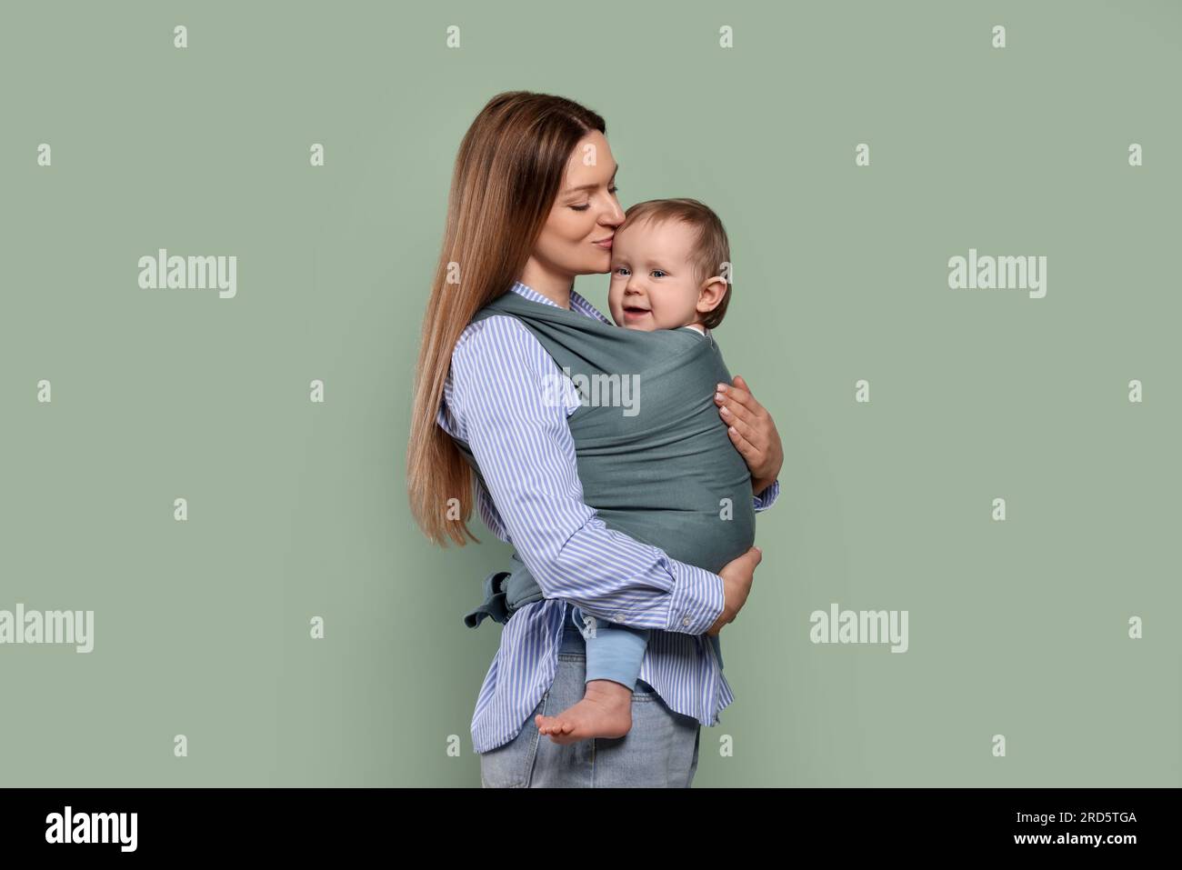 Mother holding her child in baby wrap on olive background Stock Photo Alamy