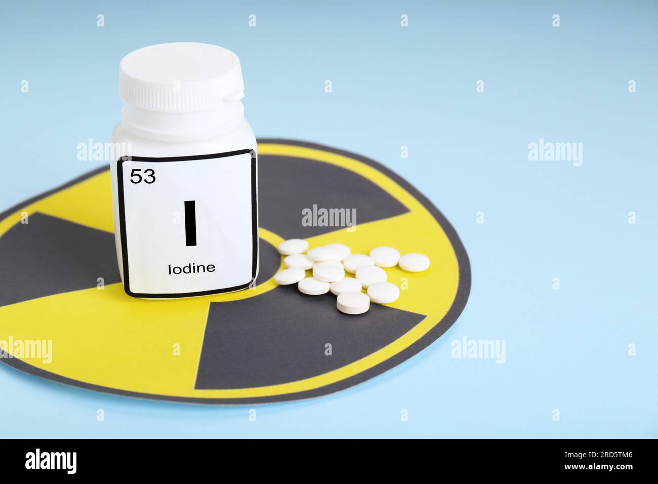 Bottle of medical iodine, radiation sign and pills on light blue