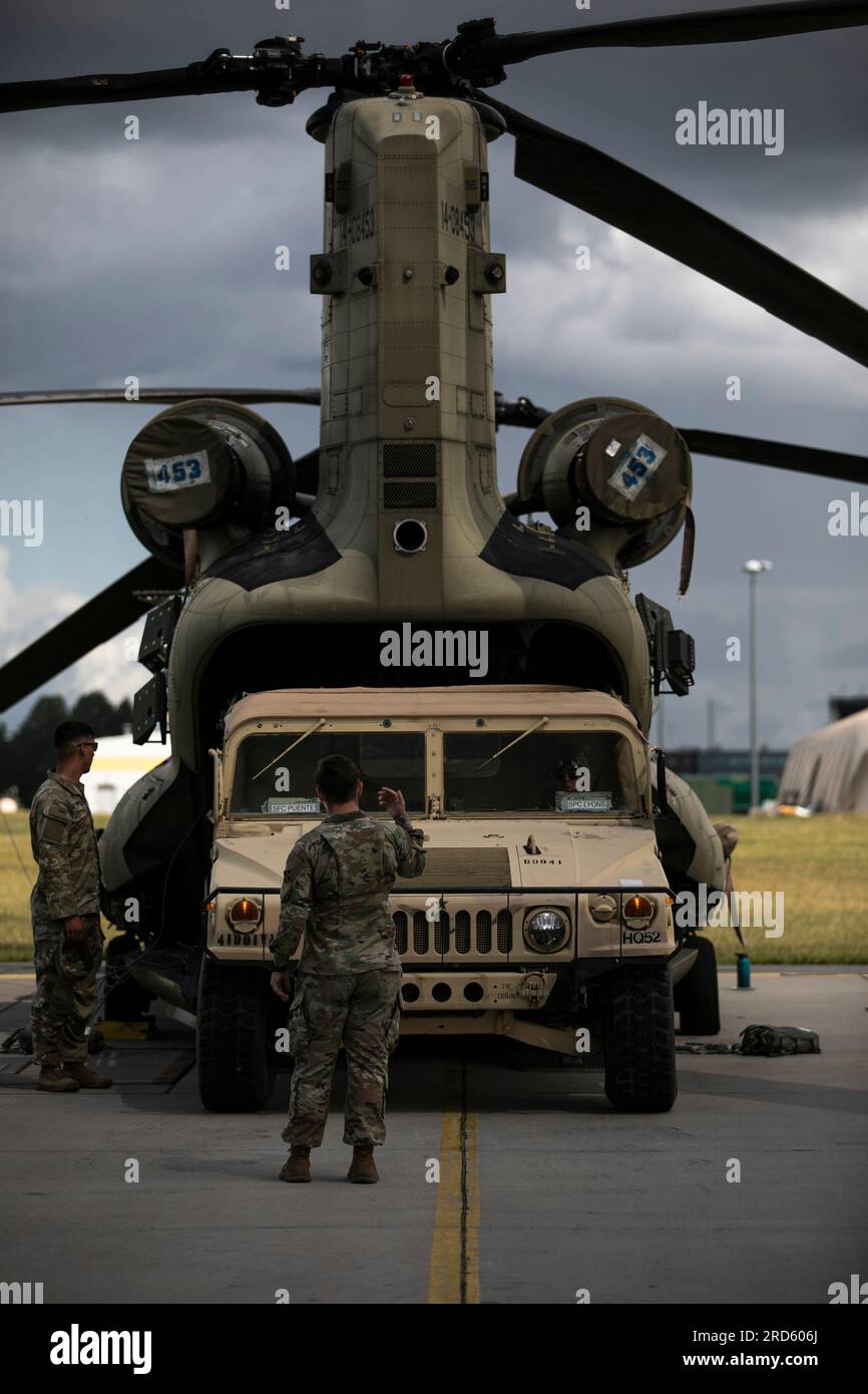 U.S. Army Spc. Caitlyn Rabb, a small arms repairman with Headquarters and Headquarters Battery, 4th Infantry Division Artillery, maneuvers an M998 Humvee into a CH-47D Chinook during cold-load training at Lielvarde Air Base, Latvia, July 18. The training, supported by crew chiefs and pilots with Task Force Knighthawk, 3rd Combat Aviation Brigade, 3rd Infantry Division supporting the 4th Infantry Division, provided the DIVARTY Soldiers an opportunity to increase their operational readiness without the risk of rotors moving on the aircraft. The 4th Inf. Div.'s mission in Europe is to engage in m Stock Photo