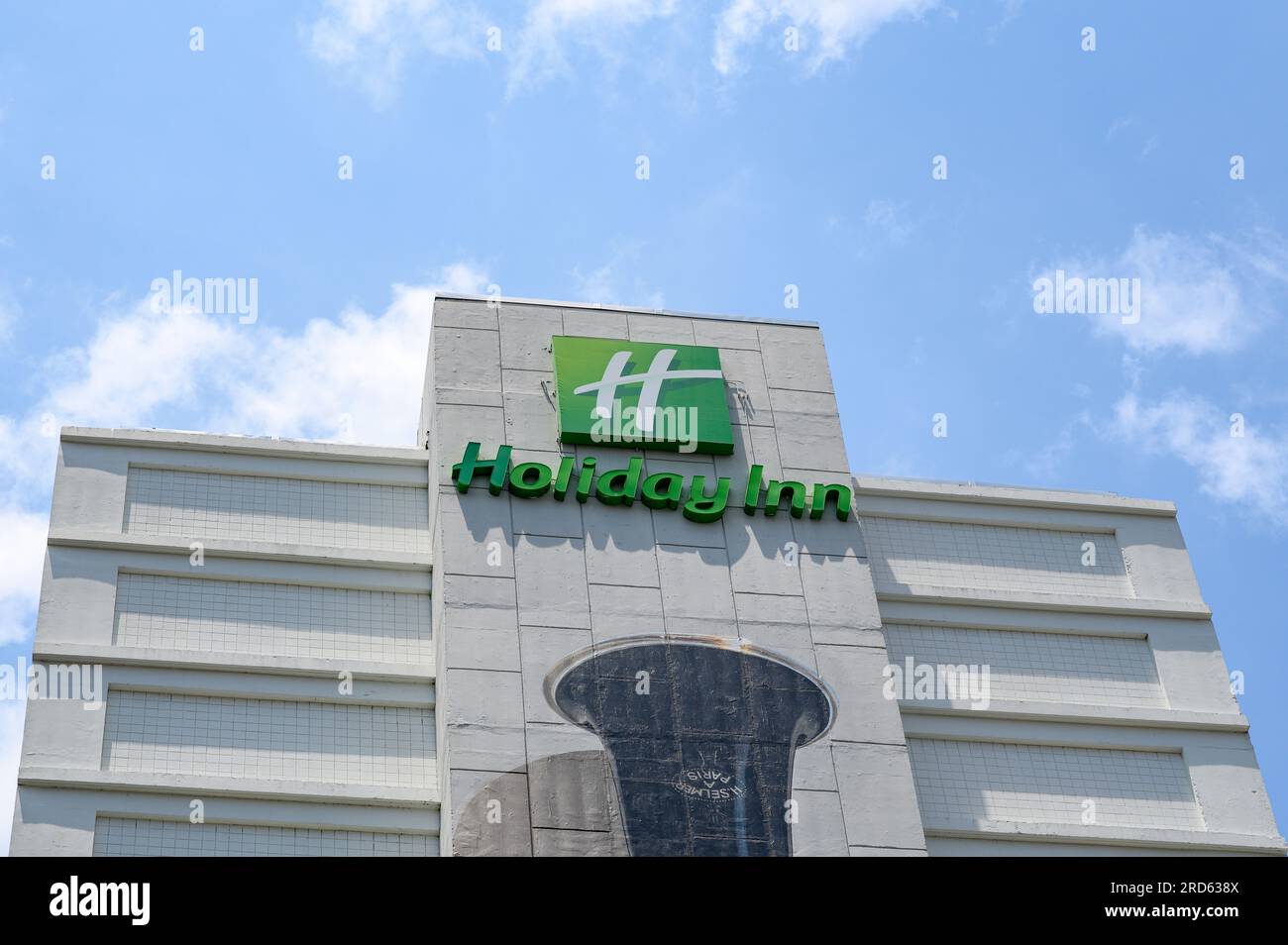 NEW ORLEANS, LA, USA - JULY 2, 2023: Side view of top section of the downtown Holiday Inn Hotel showing sign, logo and the painted bell of a clarinet Stock Photo