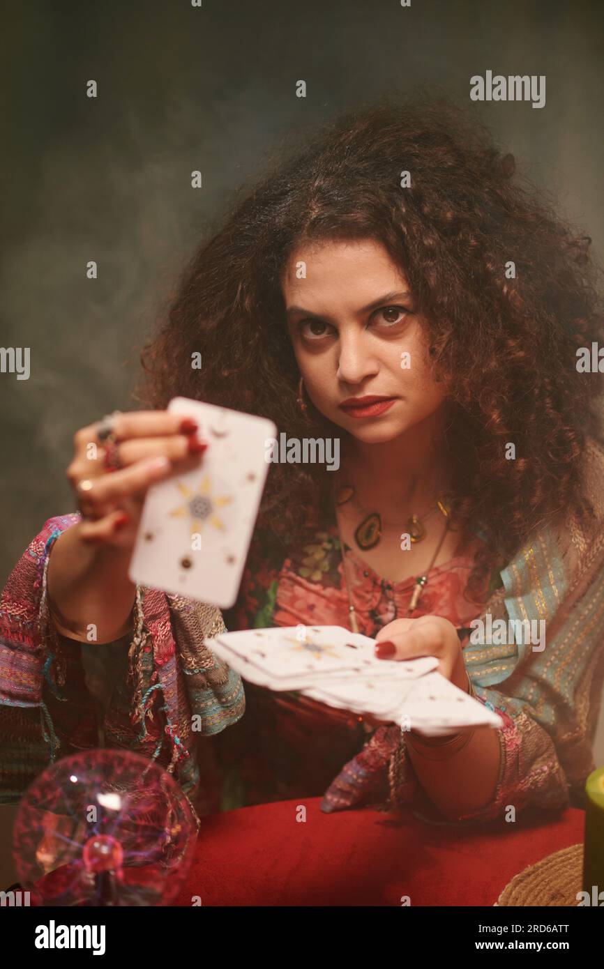 Portrait of serious sorcerer showing tarot cards, fortune telling