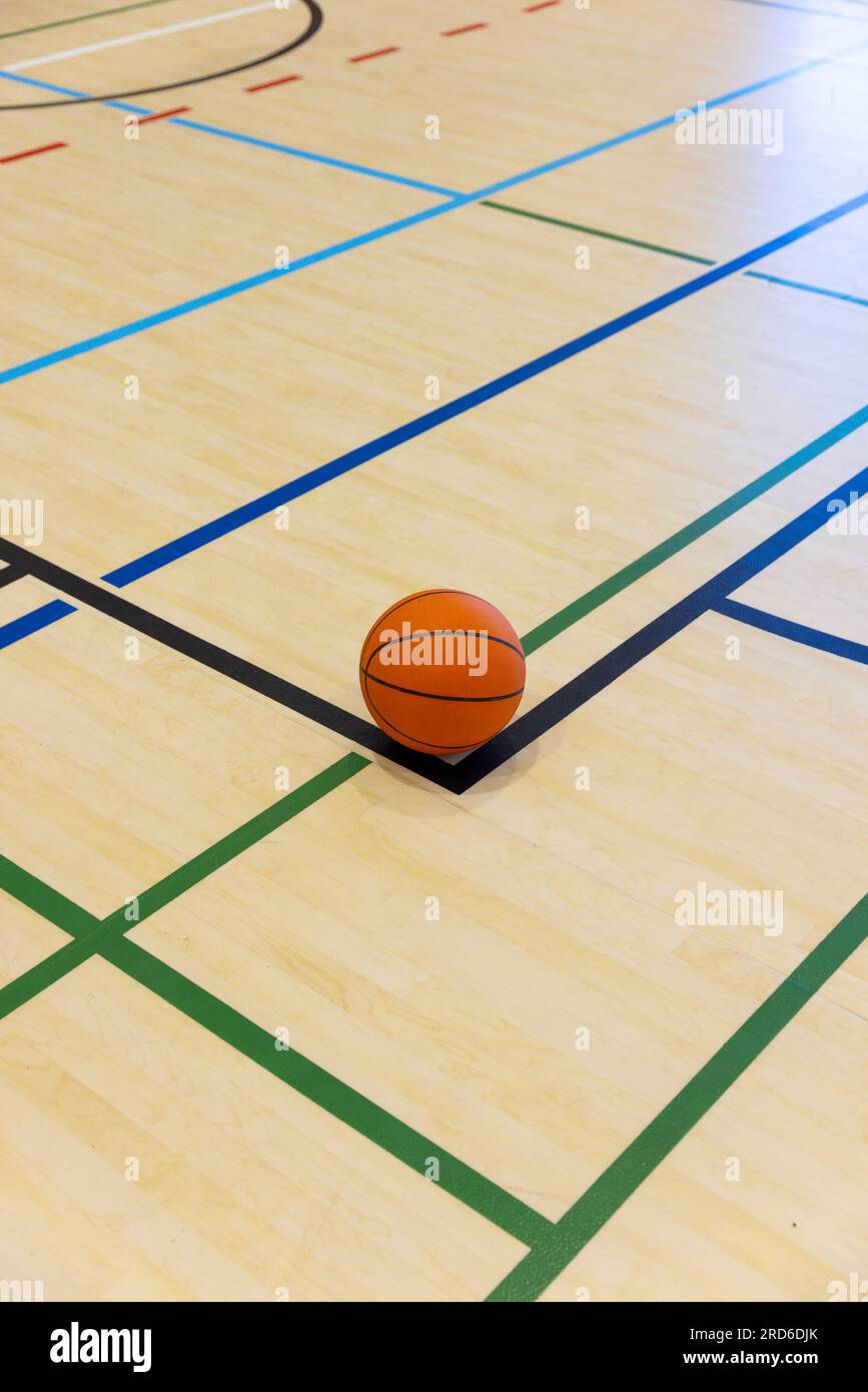 Single basketball lying on basketball court with colourful dividing lines at gym, copy space Stock Photo