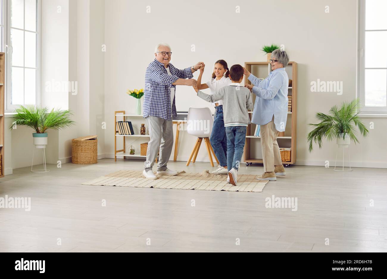 Happy grandparents and grandchildren spending time at home, dancing and having fun together Stock Photo