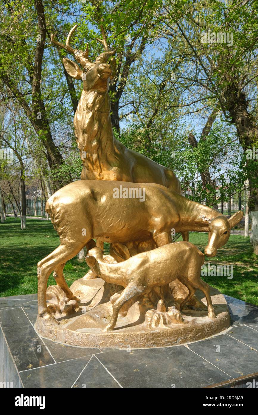 A large, concrete, painted gold sculpture, statue of a deer buck, doe